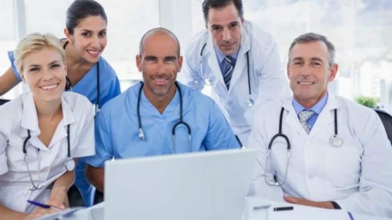 A Team of Doctors smiling looking at a laptop.