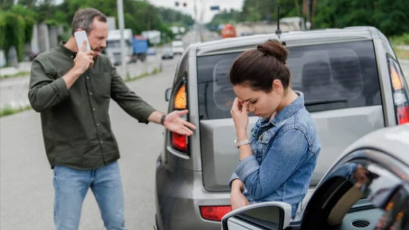 A man is talking to a woman while standing next to a car.