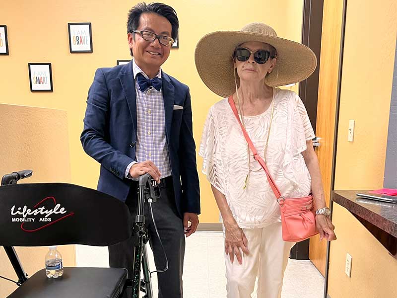 A man and woman standing next to a wheelchair.