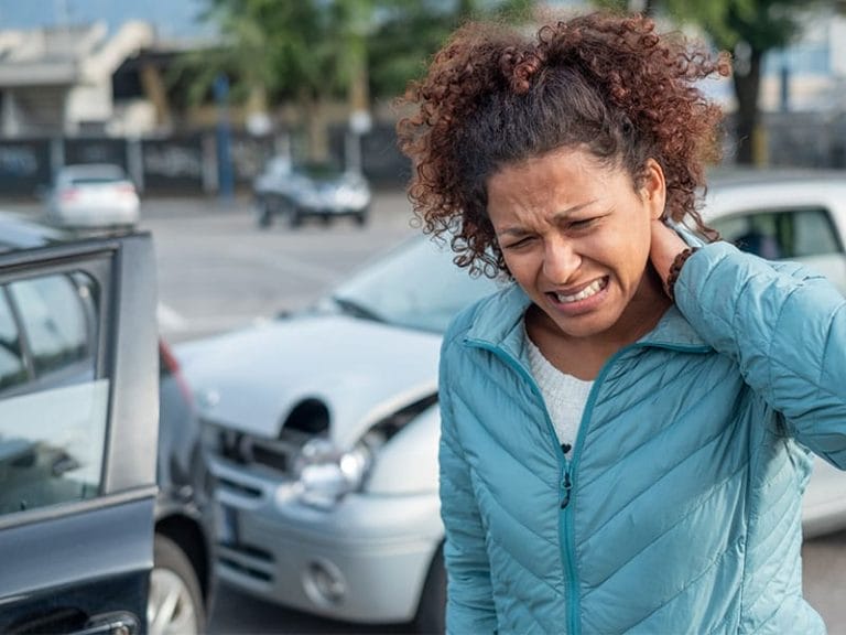 Una mujer se sujeta el cuello después de un accidente automovilístico.