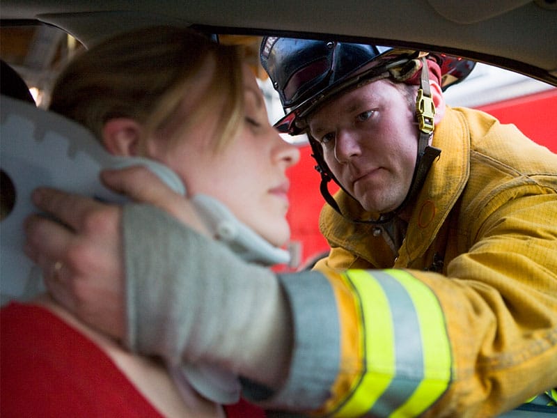 A firefighter helping a woman in a car.