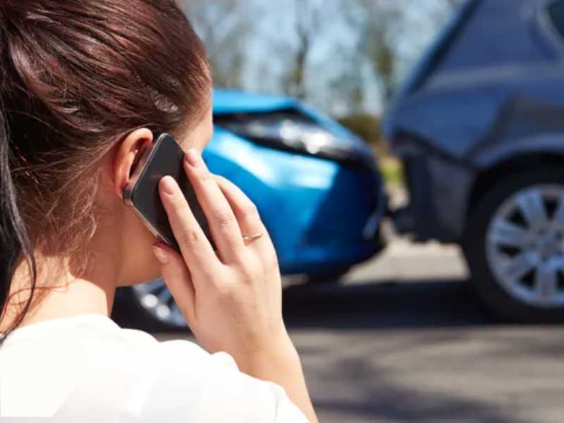 Mujer hablando por teléfono cerca de la escena de un accidente automovilístico tratando de encontrar al mejor abogado de accidentes en Phoenix.