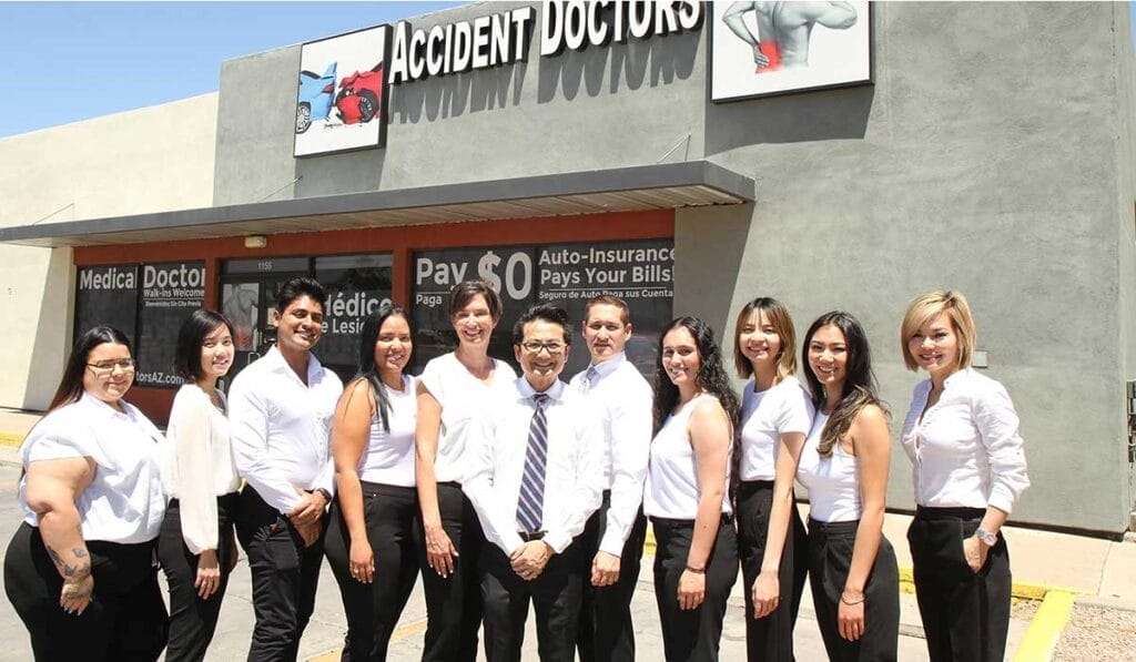Un grupo de diversos profesionales médicos vestidos de negocios parados frente a una oficina con un cartel que decía "médicos de accidentes".